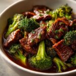 A close-up serving of tender beef chunks and bright green broccoli florets coated in a rich brown sauce, Instant Pot Beef and Broccoli.
