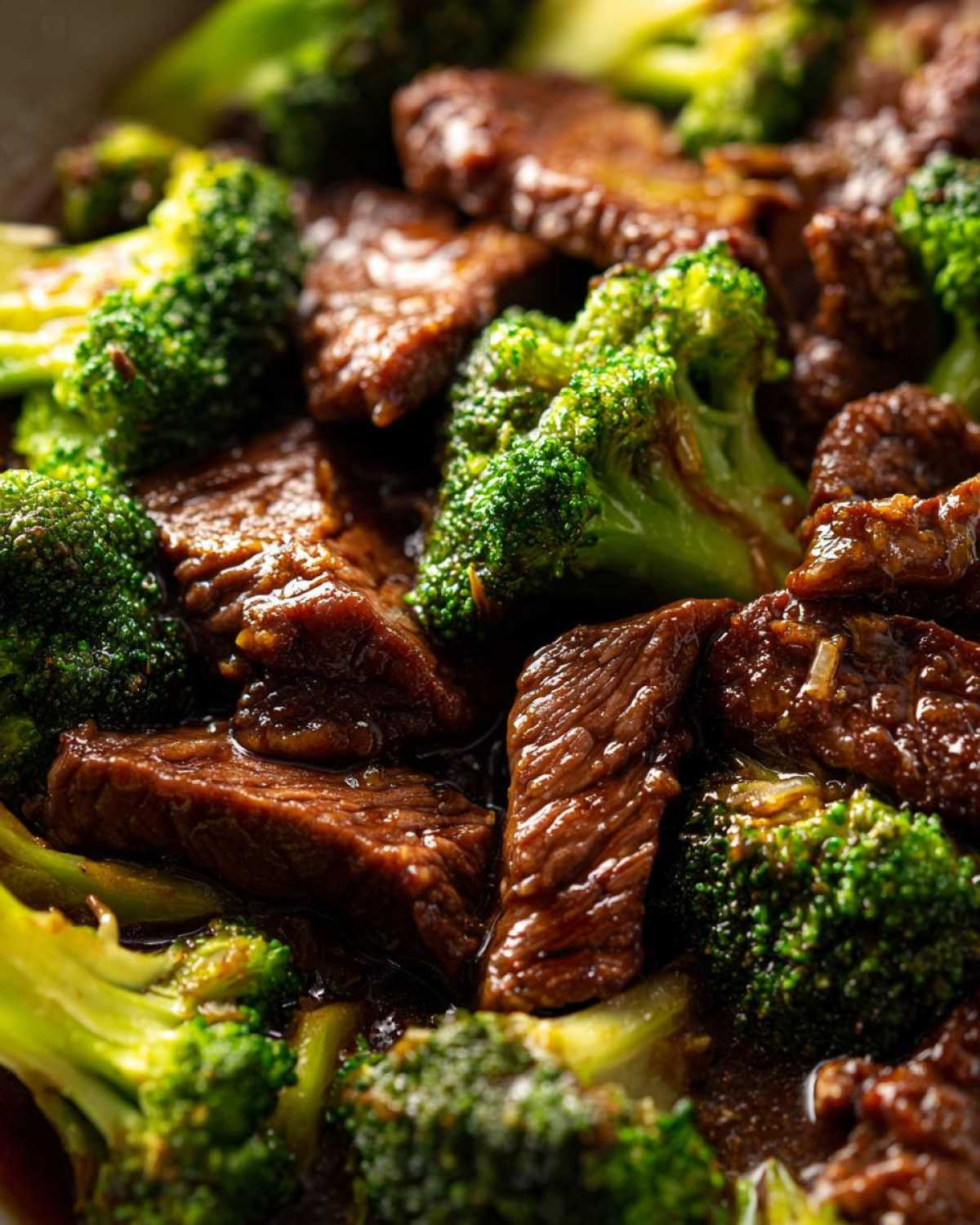 Close-up, macro shot of tender slices of beef coated in rich sauce mixed with bright green broccoli florets in Instant Pot Beef and Broccoli.