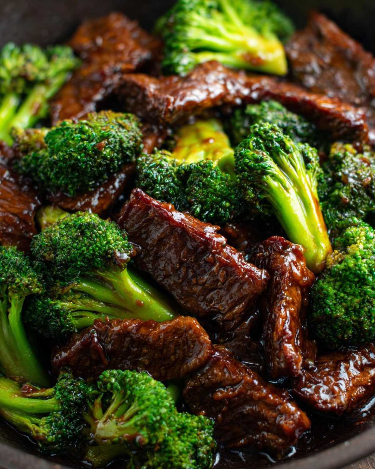 Close-up, vibrant shot of tender beef strips coated in a rich sauce mixed with bright green broccoli florets in Instant Pot Beef and Broccoli.