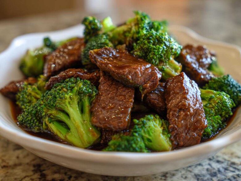 Close-up of tender beef slices coated in savory sauce mixed with bright green broccoli florets in a white bowl, showcasing Instant Pot Beef and Broccoli.