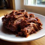 Close-up of richly seasoned, shredded Instant Pot Beef Barbacoa piled high on a white plate.