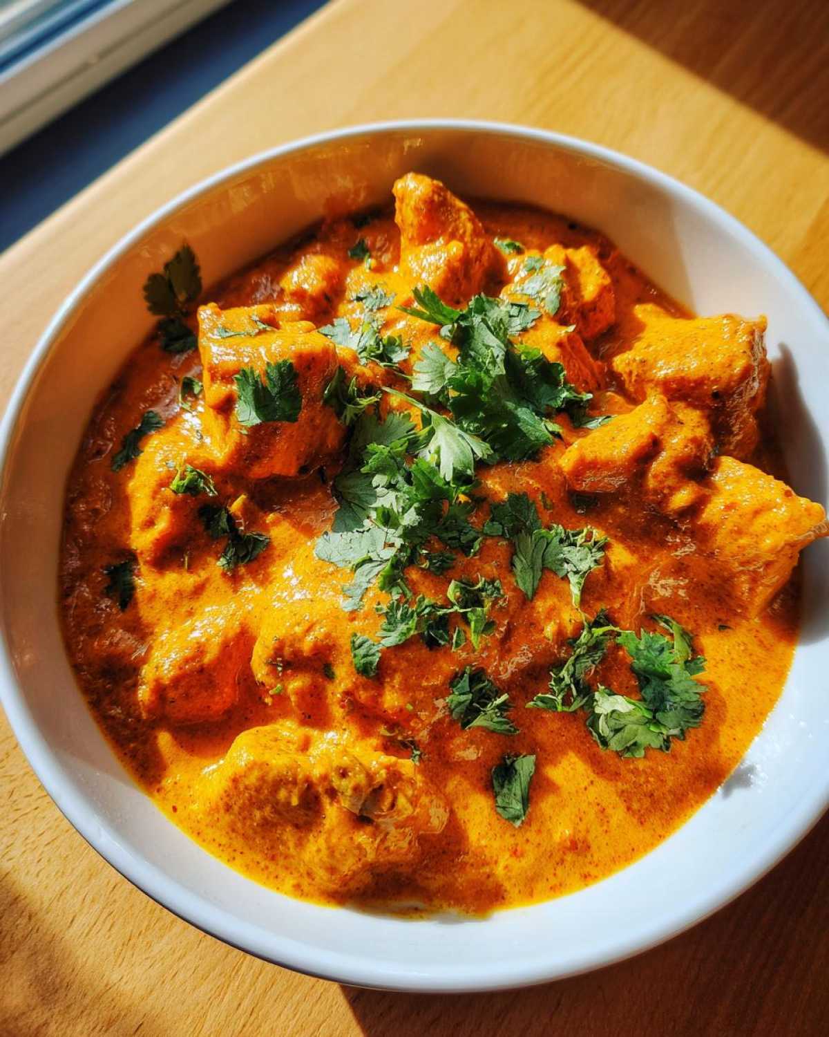 Close-up of creamy, orange Instant Pot Butter Chicken garnished with fresh cilantro.