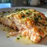 Close-up of a flaky, moist fillet of Keto Garlic Butter Salmon topped with melted butter and fresh parsley.