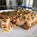 Close-up of flaky, cooked Keto Garlic Butter Salmon topped with melted garlic butter and fresh parsley.