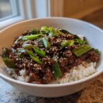 A close-up of Korean Ground Beef Bulgogi Bowls featuring savory ground beef over white rice, topped with green onions and sesame seeds.