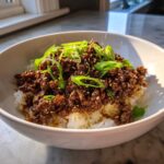 Close-up of Korean Ground Beef Bulgogi Bowls featuring savory ground beef over white rice, topped with green onions and sesame seeds.