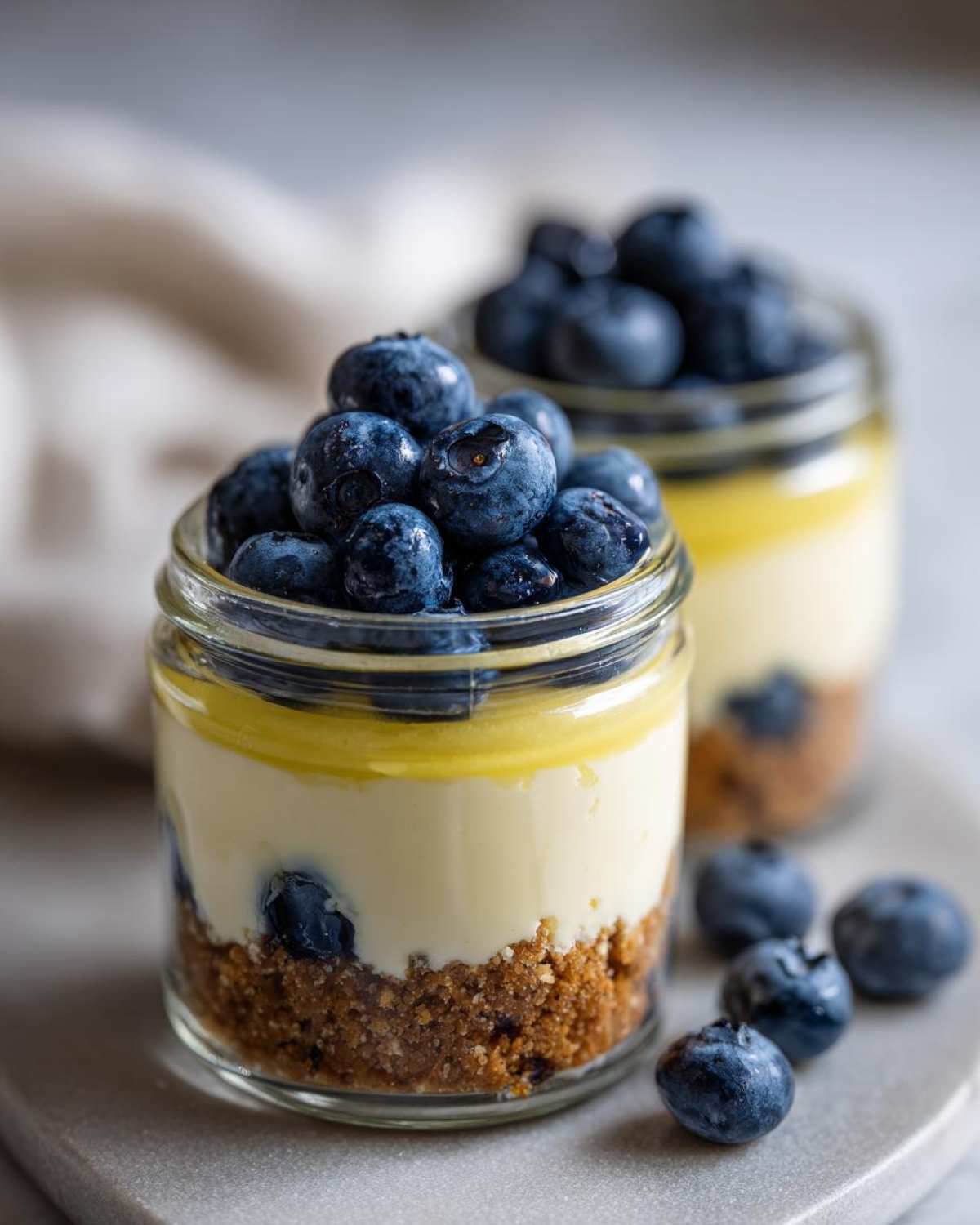 Close-up of a layered Lemon Blueberry Cheesecake Jar topped with fresh blueberries and lemon curd.