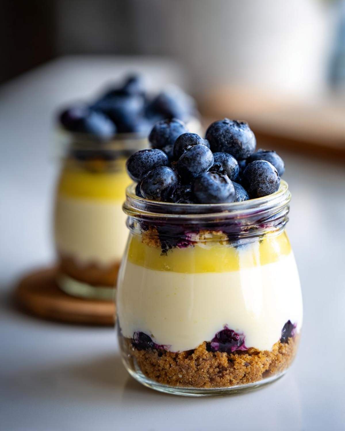 Close-up of a layered Lemon Blueberry Cheesecake Jar dessert topped generously with fresh blueberries.