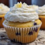 Close-up of a Lemon Blueberry Cupcake topped with swirled cream cheese frosting and lemon zest.