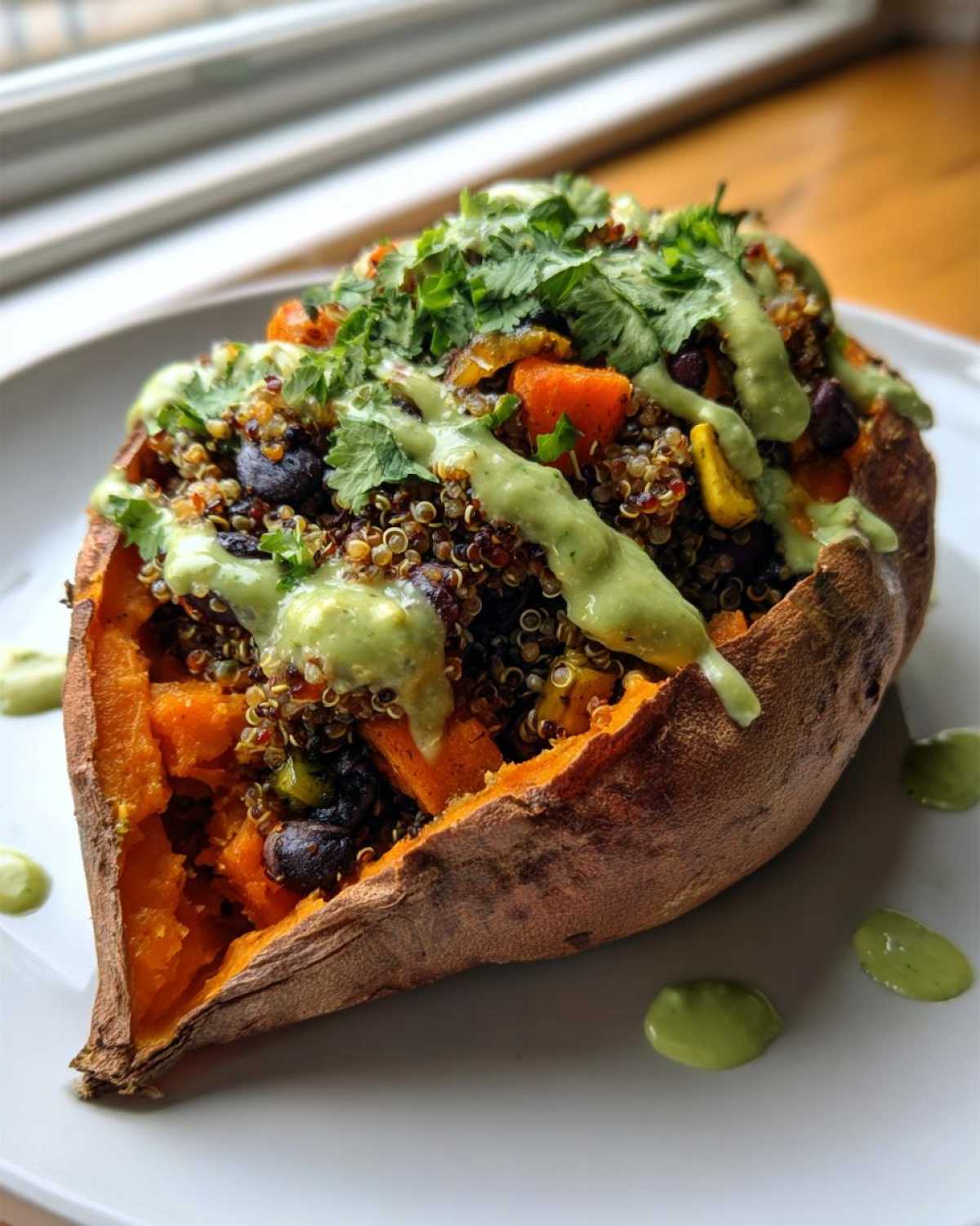 A vibrant Loaded Veggie Stuffed Sweet Potato filled with quinoa, black beans, and topped with green sauce and cilantro.
