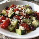 Close-up of fresh Mediterranean Cucumber Tomato Salad chunks, feta cheese, and Kalamata olives tossed in dressing.