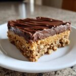 A single serving of No-Bake Chocolate Peanut Butter Oat Bars featuring a thick oat base, peanut butter layer, and chocolate topping.