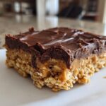 A single square of No-Bake Chocolate Peanut Butter Oat Bars showing the oat base, peanut butter layer, and chocolate topping.