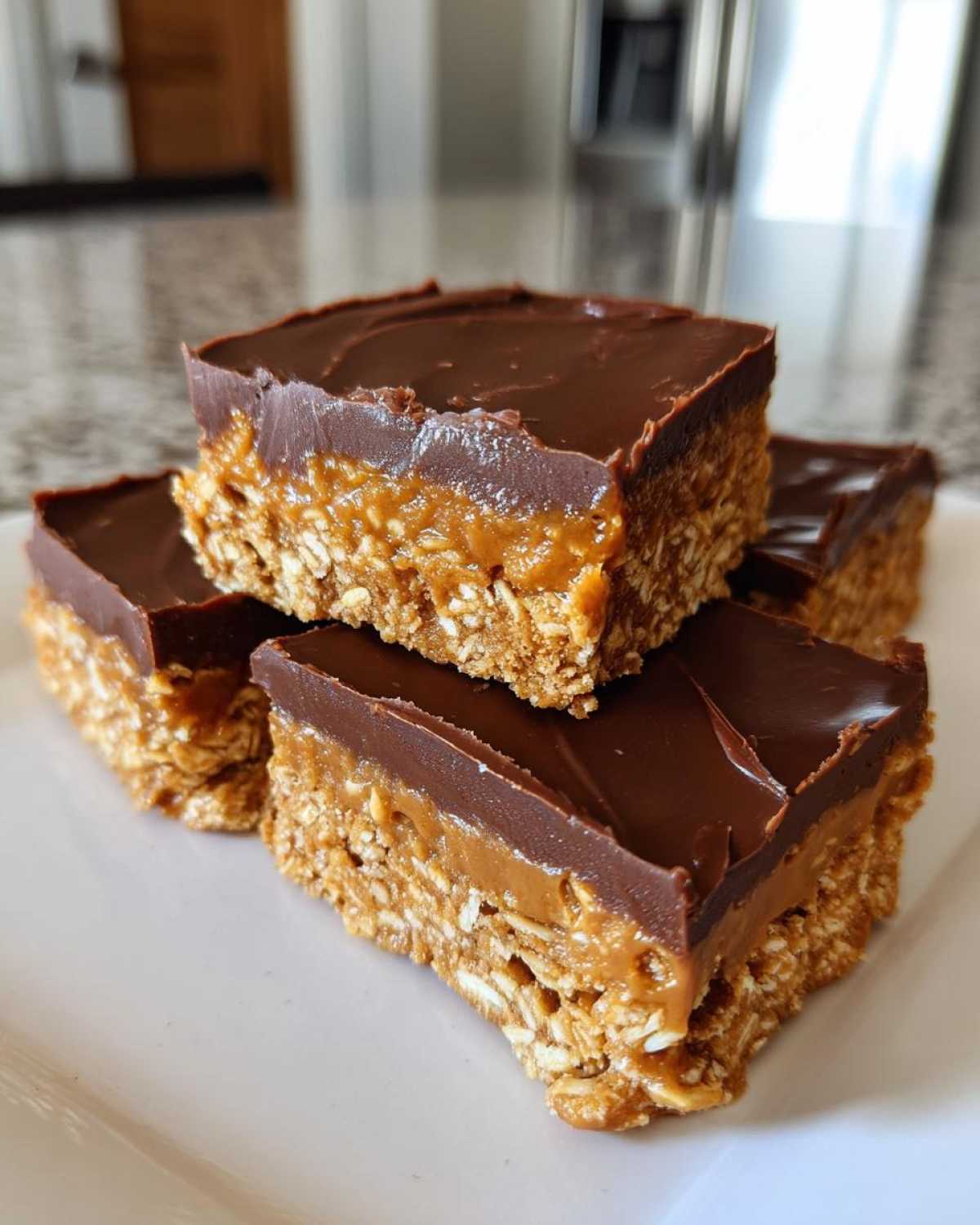 Four stacked squares of No-Bake Chocolate Peanut Butter Oat Bars with a thick chocolate topping.