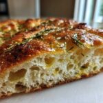 Close-up of the airy interior crumb of No-Knead Skillet Focaccia with Rosemary, glistening with olive oil.