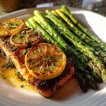 A perfectly cooked fillet of One-Pan Lemon Garlic Salmon with roasted asparagus spears and charred lemon slices.