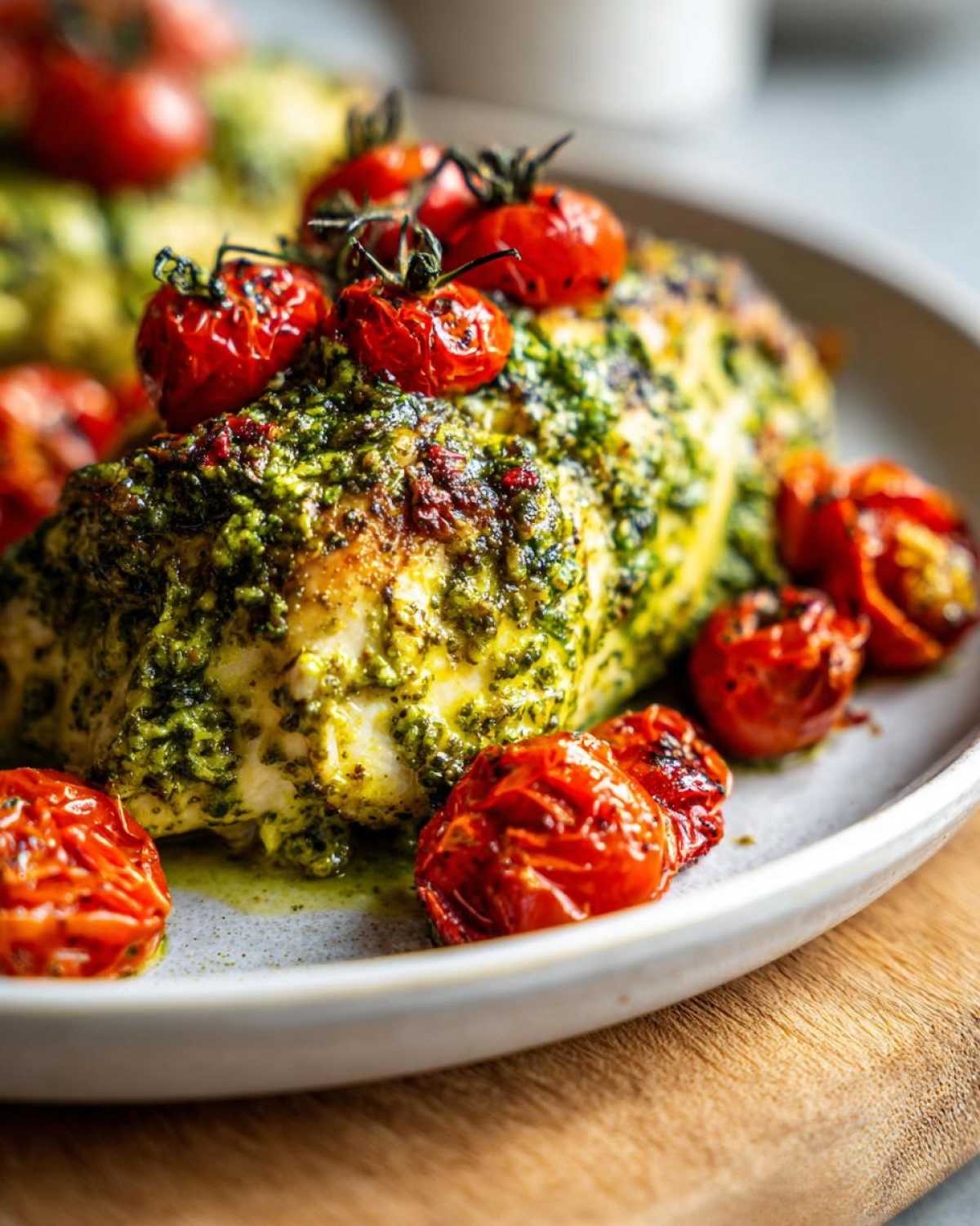 Close-up of One-Pan Pesto Chicken with Tomatoes, featuring a chicken breast topped with vibrant green pesto and roasted cherry tomatoes.