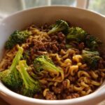Close-up of One-Pot Beef and Broccoli Ramen Noodles in a white bowl, featuring ramen noodles, ground beef, and bright green broccoli florets.