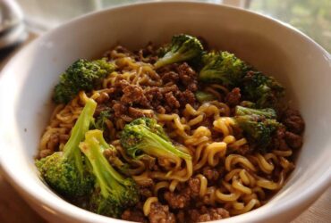 Close-up of One-Pot Beef and Broccoli Ramen Noodles in a white bowl, featuring ramen noodles, ground beef, and bright green broccoli florets.