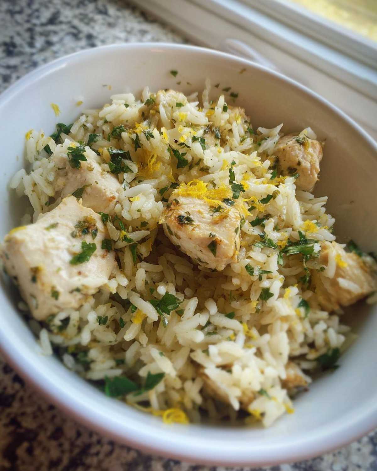 Close-up of One-Pot Chicken and Rice with Lemon and Herbs, topped with fresh parsley and lemon zest.