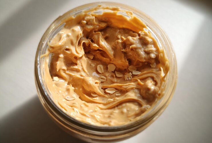 Overhead view of creamy peanut butter swirled into a jar, showing visible oat flakes for High-Protein Peanut Butter Overnight Oats.