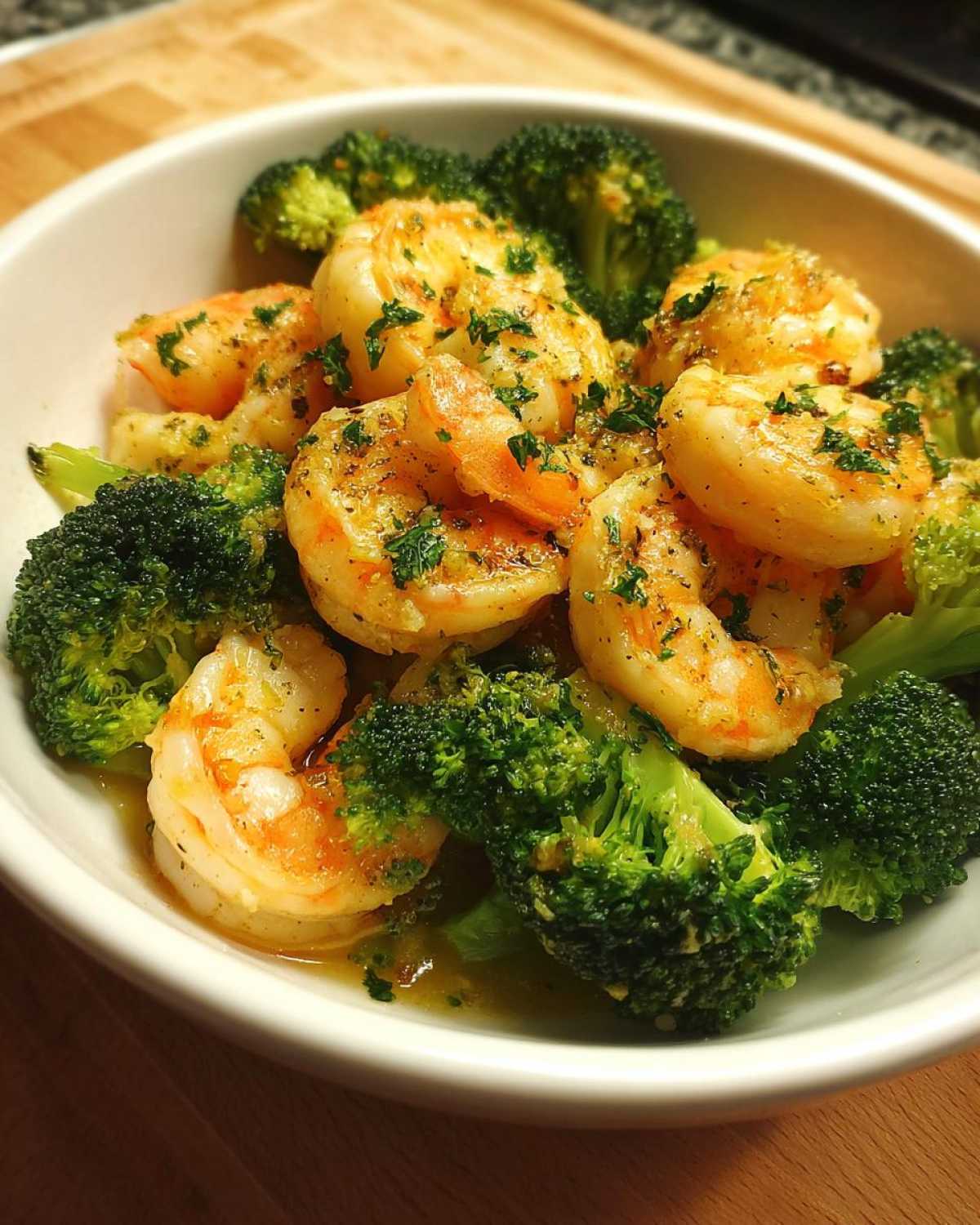 Close-up of cooked shrimp and bright green broccoli florets coated in garlic butter sauce.