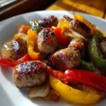 Close-up of browned sausage pieces mixed with roasted red, yellow, and green peppers and onions from Sheet Pan Sausage and Peppers.