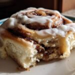 Close-up of a soft, fluffy Gluten-Free Cinnamon Rolls piece with rich cinnamon swirl and white icing.