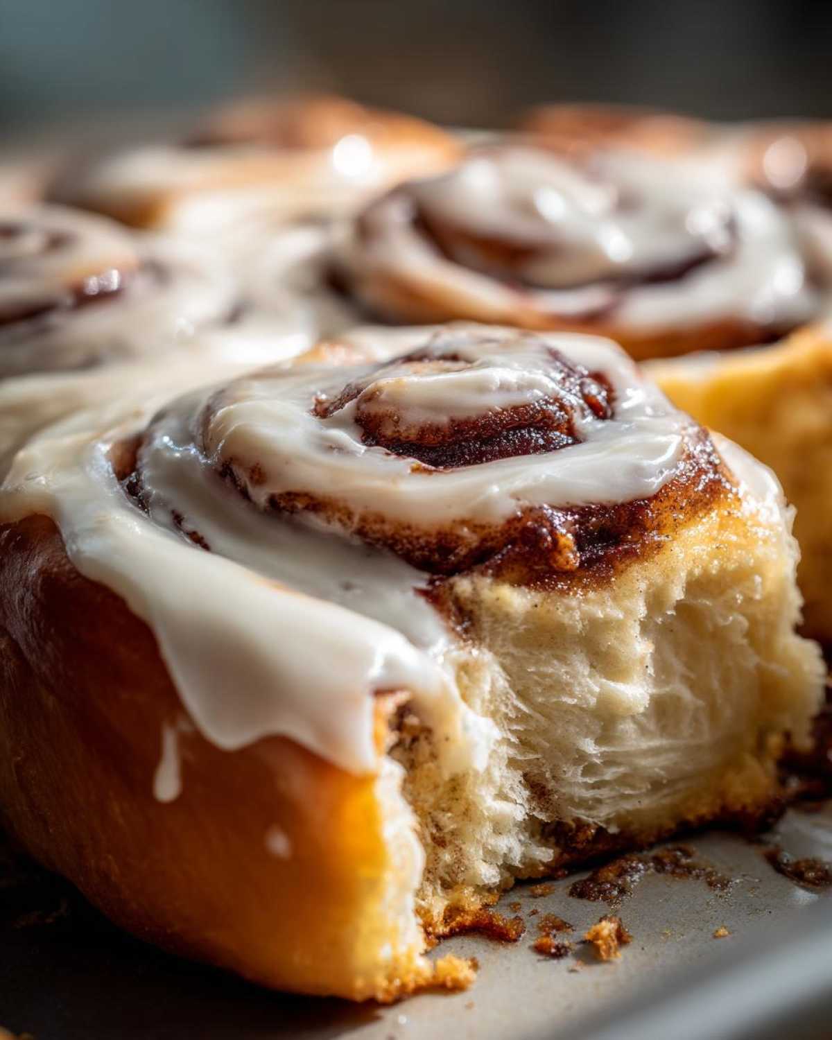 A close-up shot showing the soft, fluffy texture of a Gluten-Free Cinnamon Roll with thick white icing.