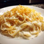 Close-up of creamy Spaghetti Squash Alfredo tossed in white sauce and topped with grated cheese.