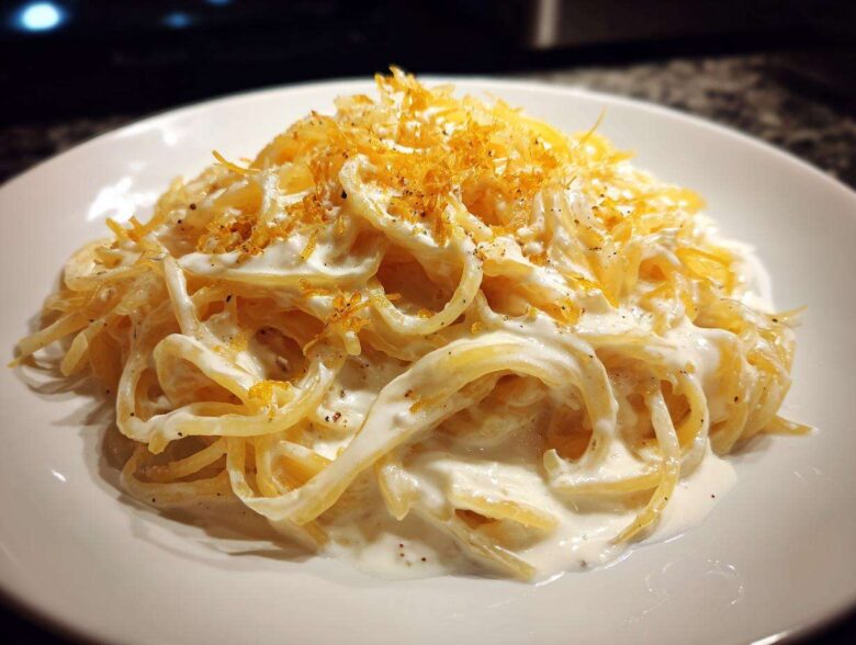 Close-up of creamy Spaghetti Squash Alfredo tossed in white sauce and topped with grated cheese.