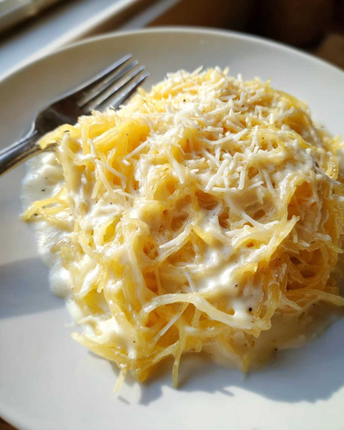 Close-up of a serving of Spaghetti Squash Alfredo topped generously with shredded Parmesan cheese.