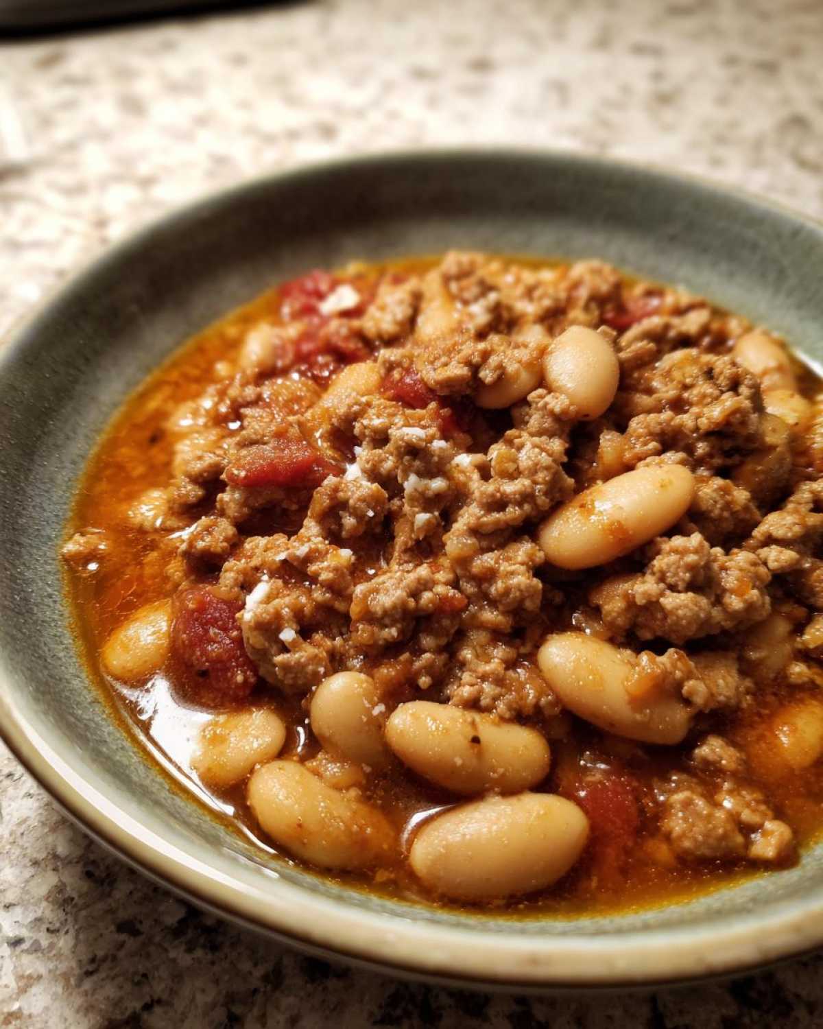 A close-up of a hearty serving of Spicy Turkey White Bean Chili featuring ground turkey and white beans in a rich, reddish broth.