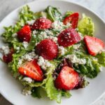 Close-up of a vibrant Spring Mix Salad with Strawberries and Goat Cheese served on a white plate.