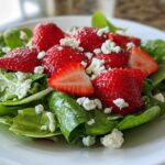 Close-up of a vibrant Spring Mix Salad with Strawberries and Goat Cheese on a white plate.