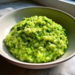 Close-up of creamy Spring Pea and Mint Risotto, bright green with whole peas and fresh herbs, served in a light bowl.