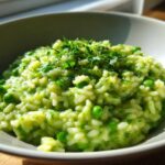 Close-up of creamy Spring Pea and Mint Risotto, topped with fresh chopped herbs, served in a light grey bowl.