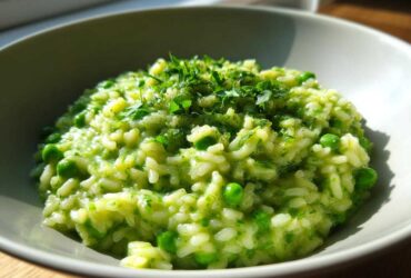 Close-up of creamy Spring Pea and Mint Risotto, topped with fresh chopped herbs, served in a light grey bowl.