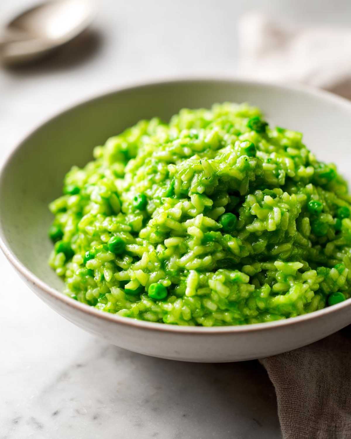 Close-up of creamy, bright green Spring Pea and Mint Risotto served in a light bowl.