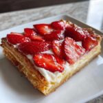 A close-up, appetizing photo of a single Strawberry Cream Cheese Danish slice on a white plate.
