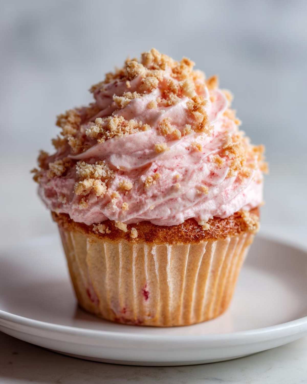 A single, perfectly baked Strawberry Crunch Cupcakes topped with swirled pink frosting and crunchy crumble.