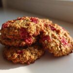 A close-up stack of golden brown Strawberry Oatmeal Breakfast Cookies studded with bright red fruit pieces.