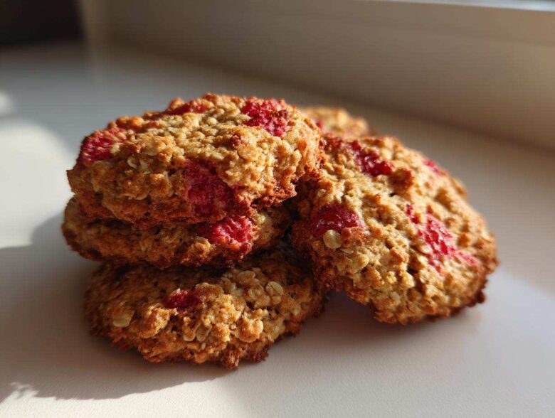A close-up stack of golden brown Strawberry Oatmeal Breakfast Cookies studded with bright red fruit pieces.