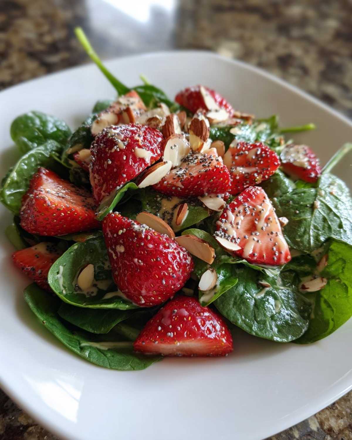 Close-up of a fresh Strawberry Spinach Salad with poppy seed dressing and sliced almonds.