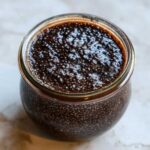 Overhead close-up of thick Vegan Chocolate Chia Pudding texture inside a small glass jar.