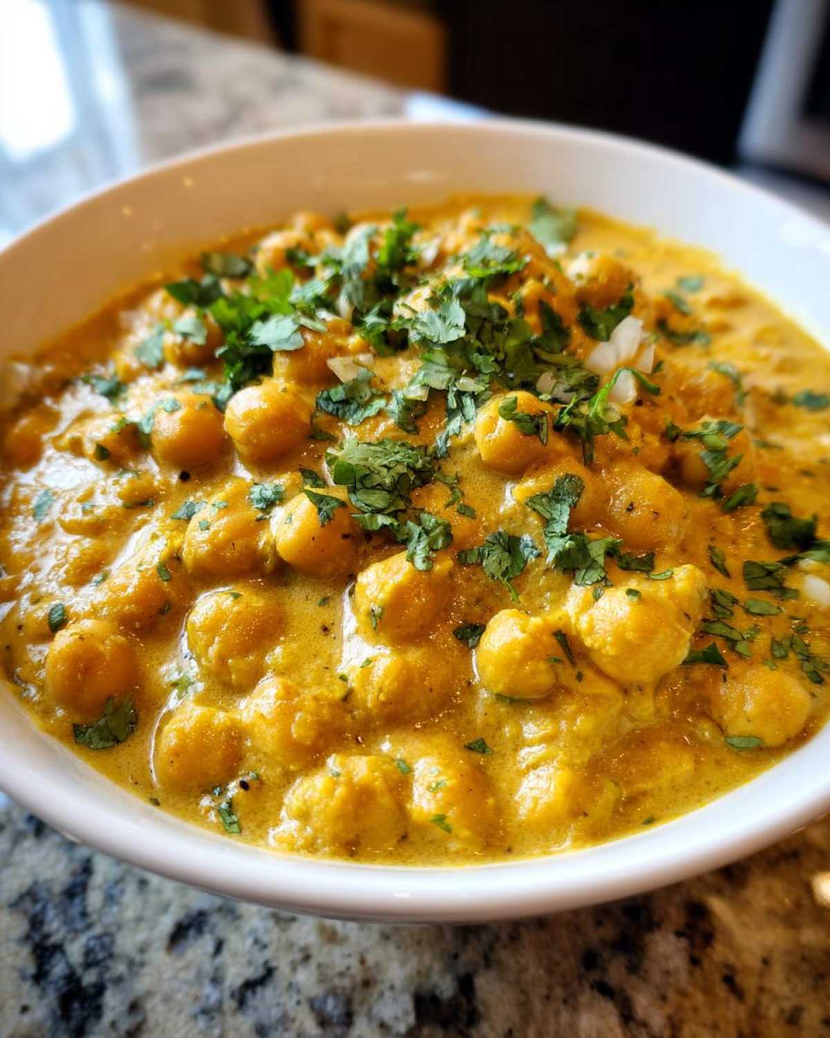 Close-up of a bowl filled with creamy Vegetarian Chickpea Curry with Coconut Milk, garnished with fresh cilantro.