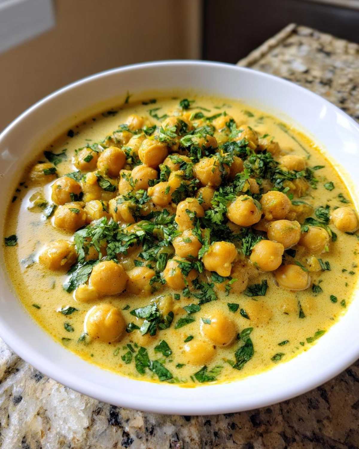 Close-up of a white bowl filled with Vegetarian Chickpea Curry with Coconut Milk, topped with fresh cilantro.