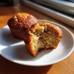 Two Banana Walnut Cottage Cheese Muffin Breakfast items on a white plate, one bitten into showing the moist interior and walnuts.
