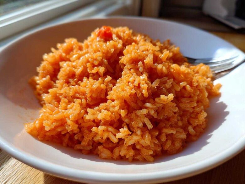 A close-up of fluffy, orange-colored Spanish Rice served in a white bowl, ready to eat.