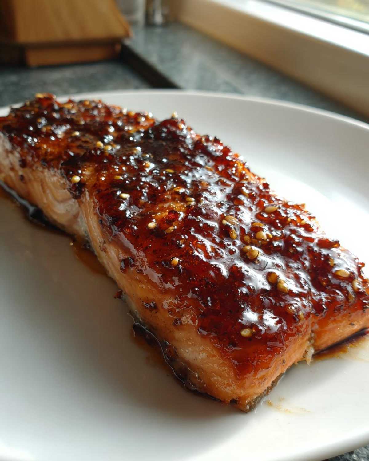 Close-up of a perfectly cooked salmon fillet topped with thick, shiny Brown Sugar Teriyaki Salmon Glaze and sesame seeds.
